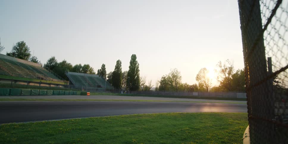 The curve of a race track in front of empty stands in the evening