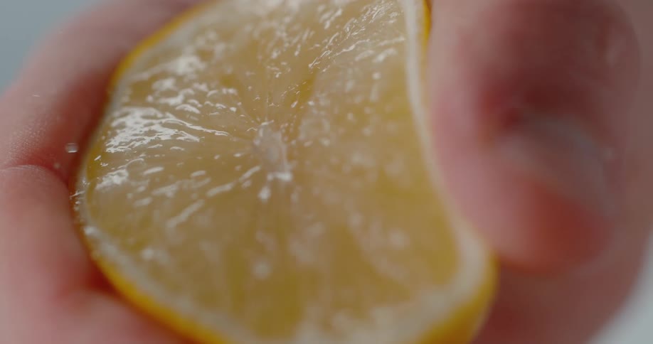 A close up of a person squeezing a lemon to get juice out of it