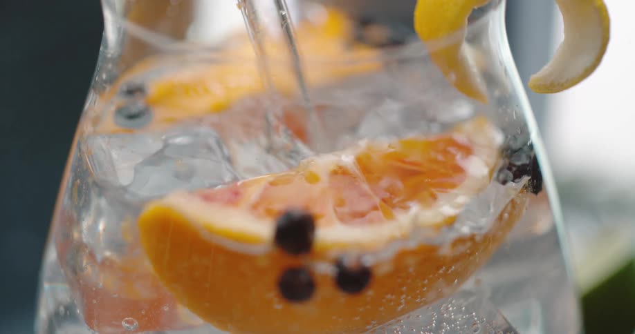 An iced drink with orange slices and ice cubes stirred inside a cocktail glass