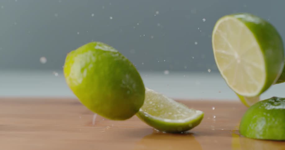 Lime slices dropping in slow motion on water on cutting board