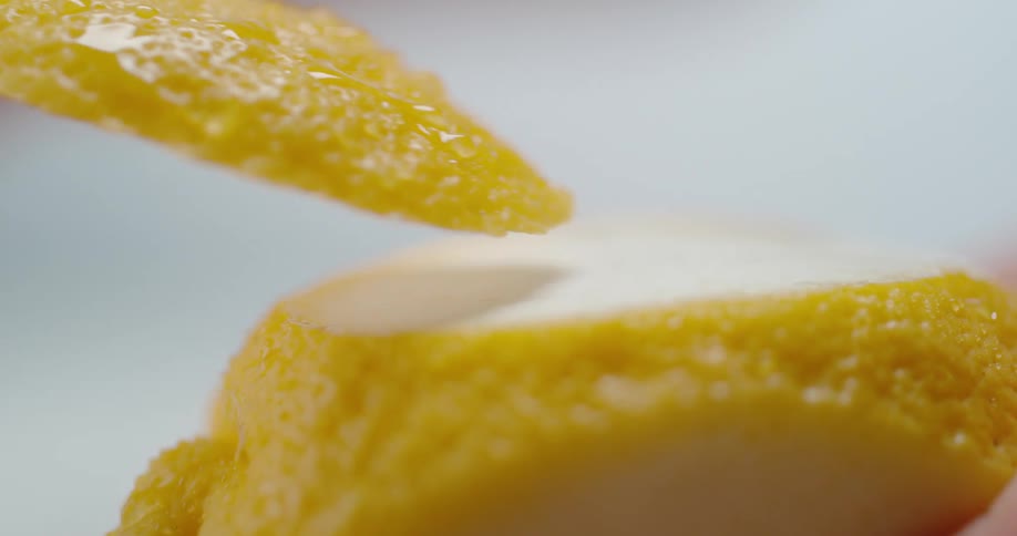 A sharp knife cuts across the surface of a lemon and slices a piece off
