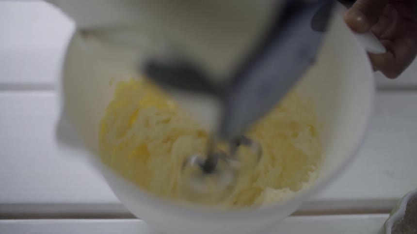 A person using a hand mixer on to mix a white substance