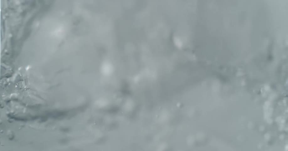 Water pouring over ice cubes and bubbles are rising up