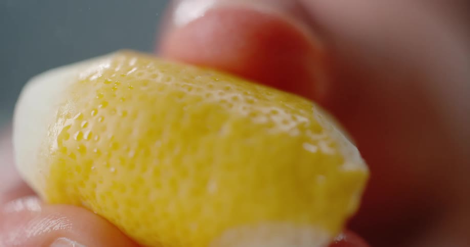 A person squeezing a lemon with two fingers