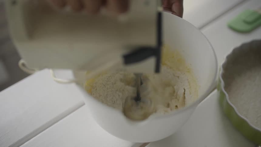 Person using hand mixer to stir food in bowl