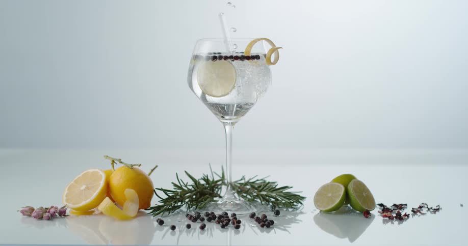 Crystal clear liquid pouring inside a cocktail glass with lemon slices floating inside