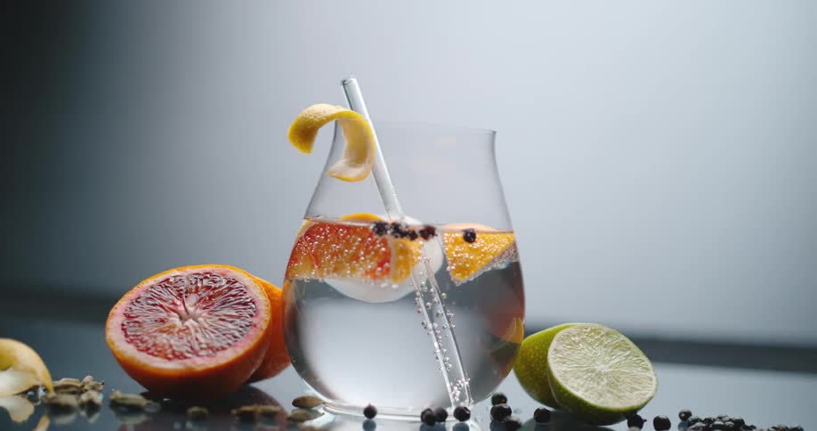 Citrus floats in clear liquid in a glass with a straw and bubbles