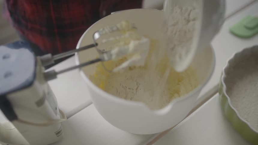 Flour is being poured into a mixing bowl