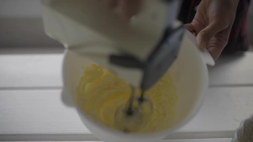 Beaters mix something yellow in a bowl