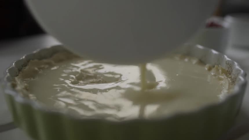 Someone pouring filling in a pie crust
