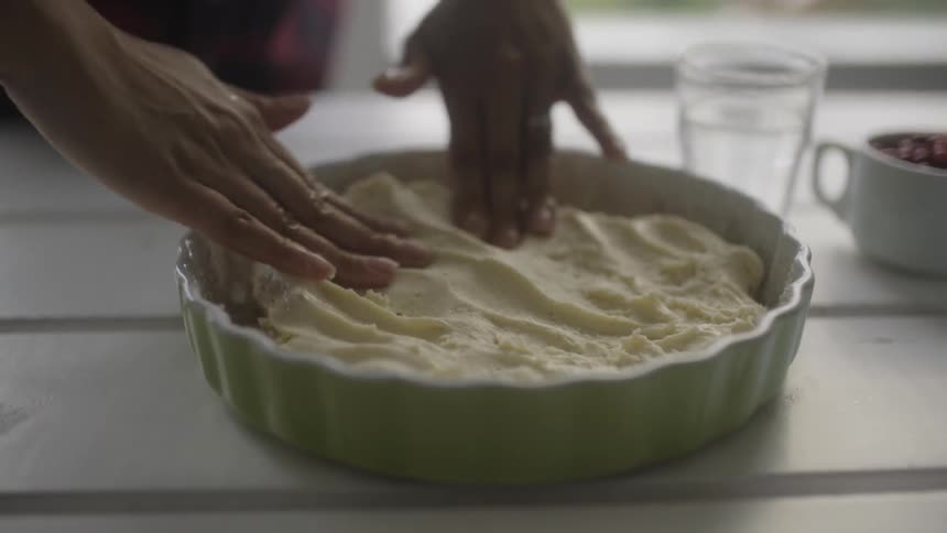 A person is spreading food in a cake pan