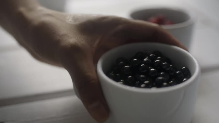 A woman picking up a mug filled with berries