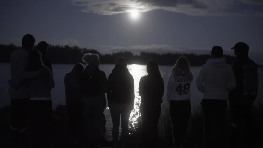 A group of people sit near the water together