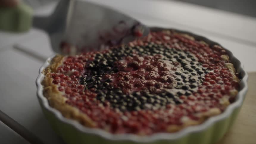 A person cuts into a multi-berry pie