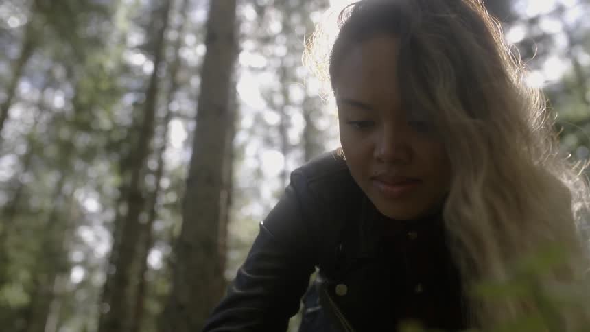 A woman leaning over in a forest