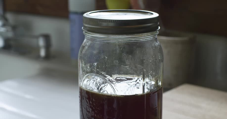 Mason jar sits with sunlight beaming through honey