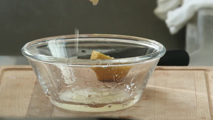 A person is squeezing lemons into a bowl