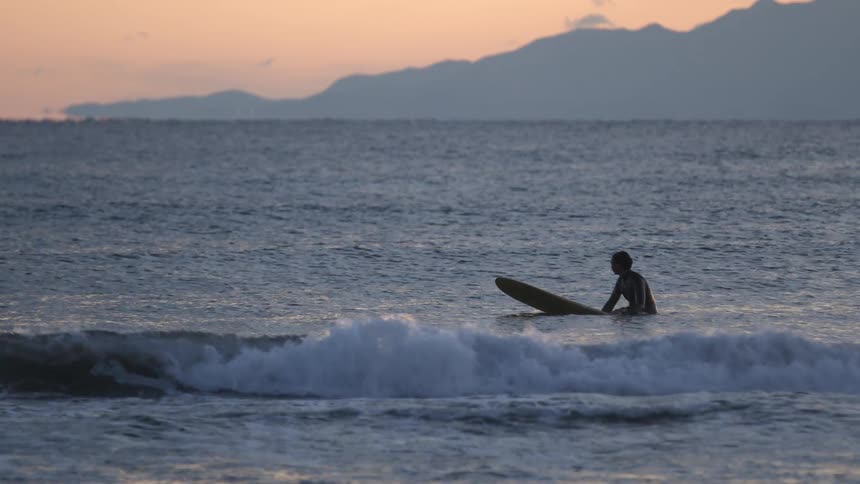 A person sitting on a surfboard in the ocean