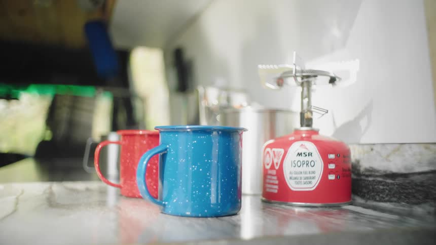 A vehicle with a table with cups and a sink and a faucet in the background