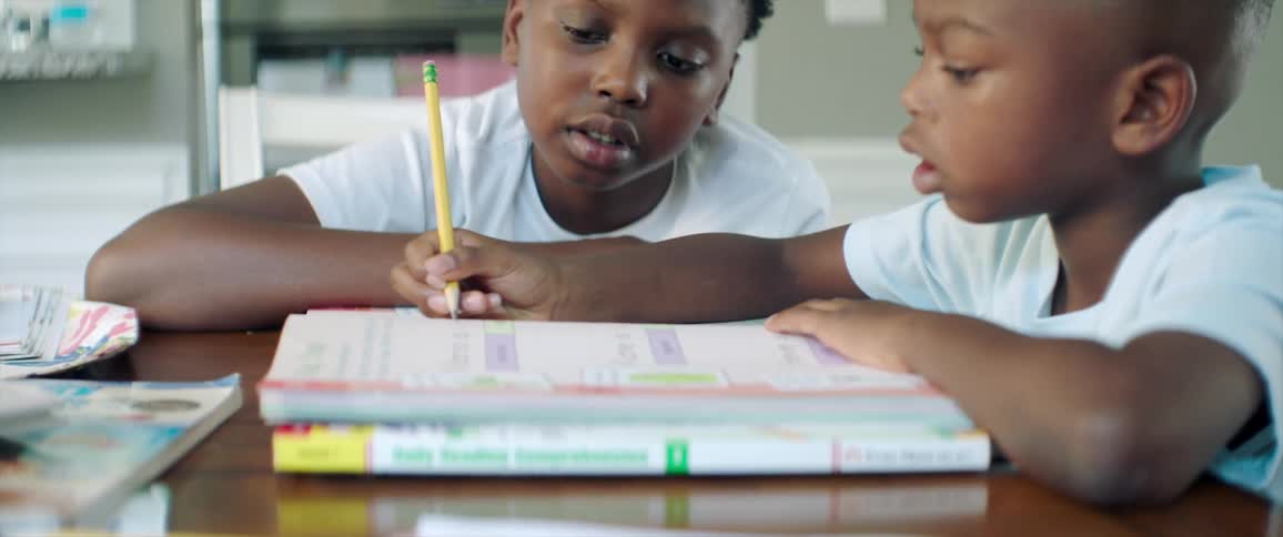 A pair of boys do homework together at a table