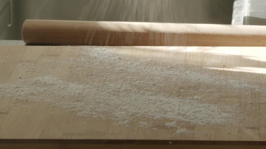 Flour is being put on a cutting board