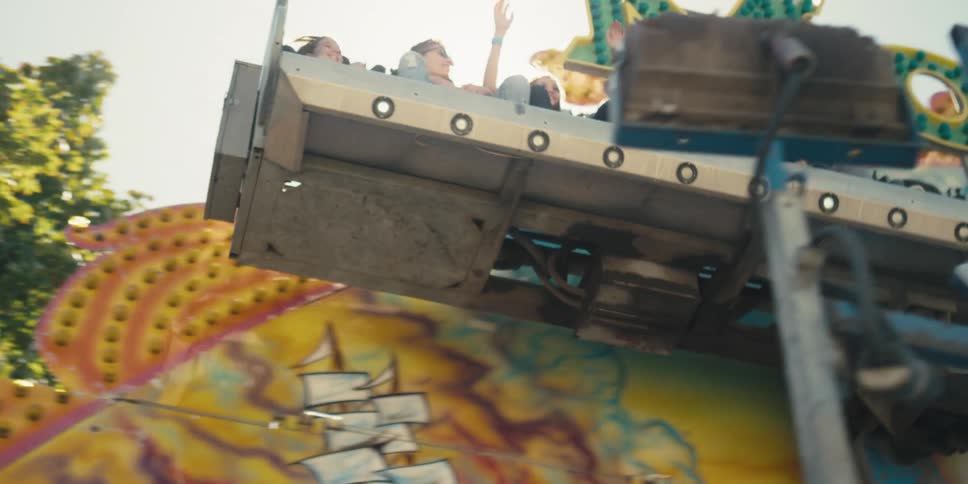 Young people smiling while on an amusement park ride on a sunny summer day