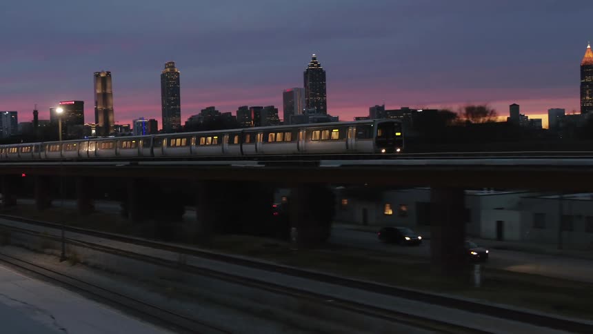 Metro train commuting across a bridge in the city at sunset