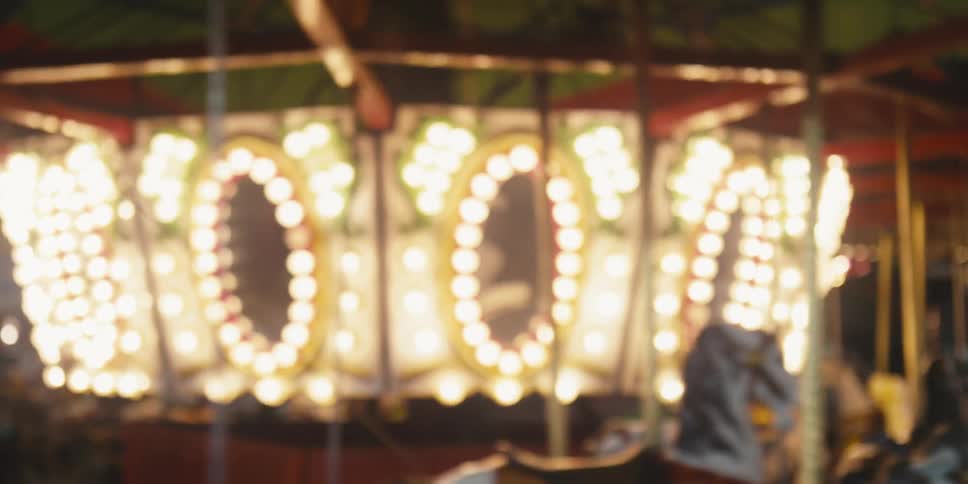 An empty carousel with horses lit up spinning around at nighttime