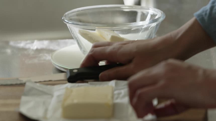 A person puts butter slices in the bowl
