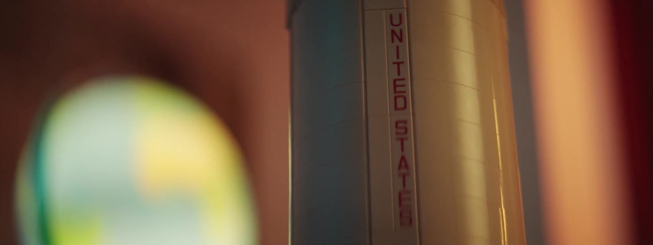 Close up of a toy rocket model standing on a table inside a dimly lit room