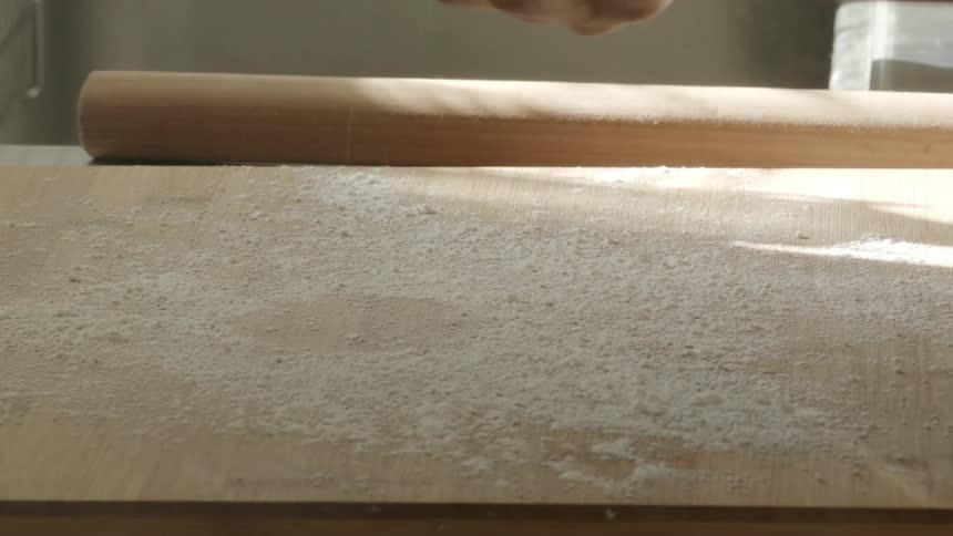 A person kneading dough over a well floured table using the hands