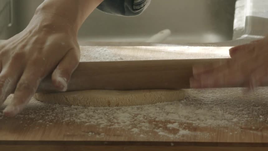 A person is using a rolling pin to flatten dough