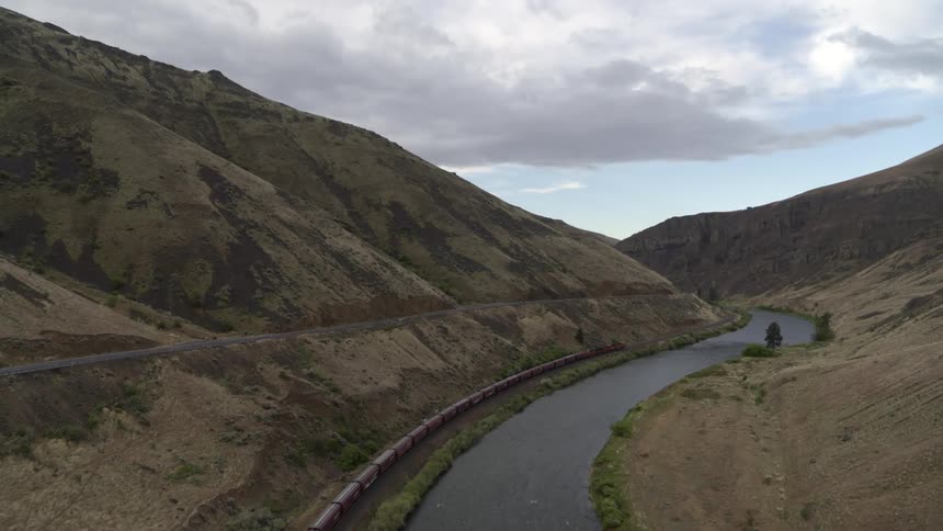 A freight train snakes its way through a winding river valley