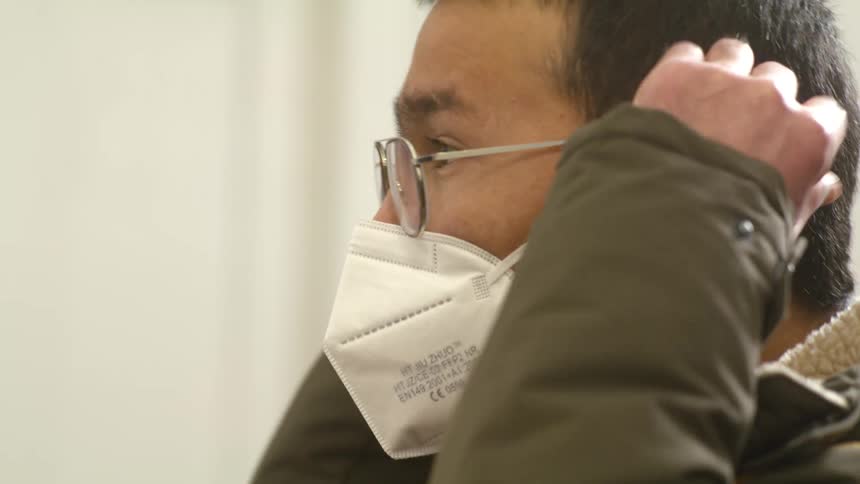 Profile of an asian man putting on a facial mask indoors