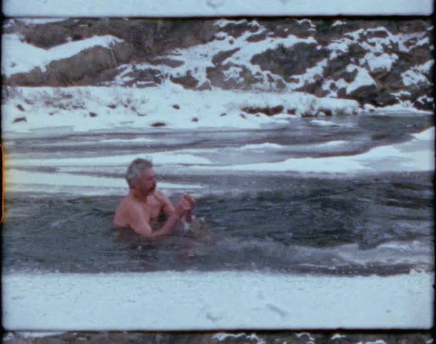 A man that is sitting down in a frozen river