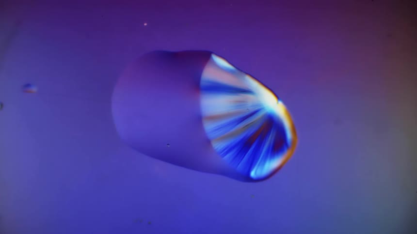 A liquid slowly turns into crystals over a magenta surface