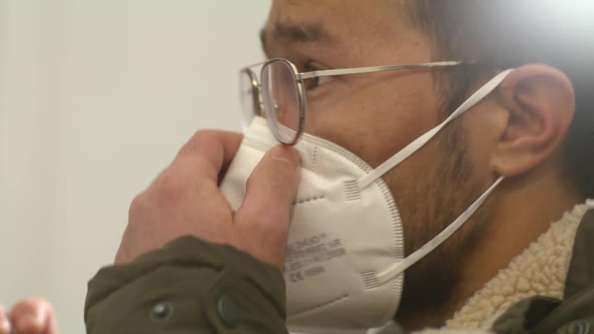 Close up of a man putting a mask on and adjusting his glasses