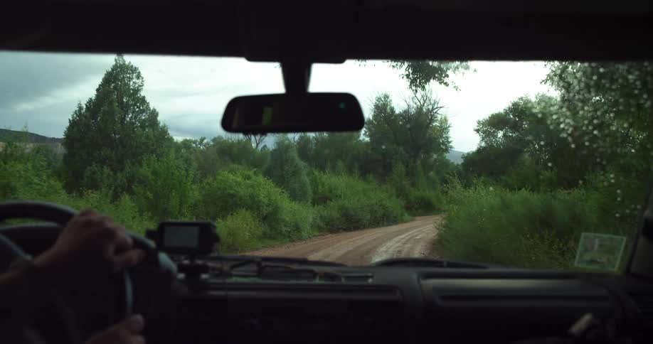 A man driving a car on a rural dirt road at day time