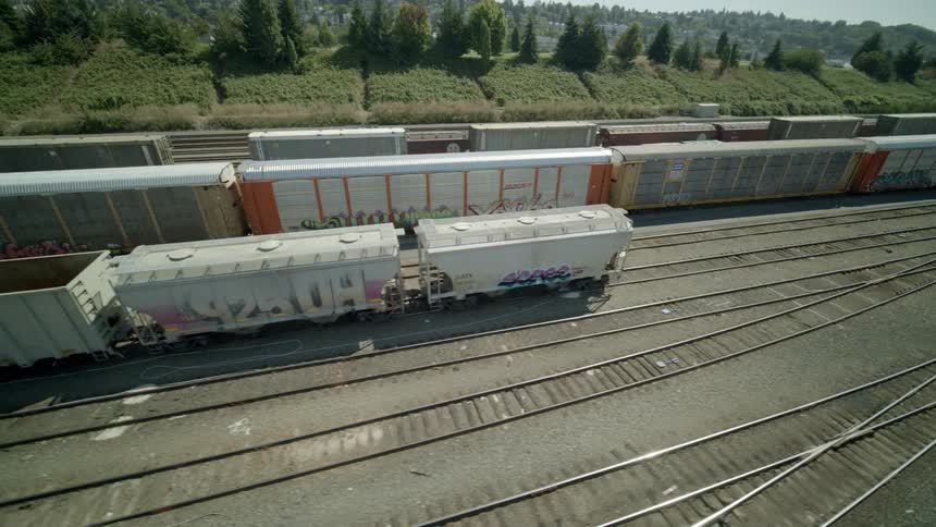 Orbit around railroad cars sitting idle at a freight yard on a summer day