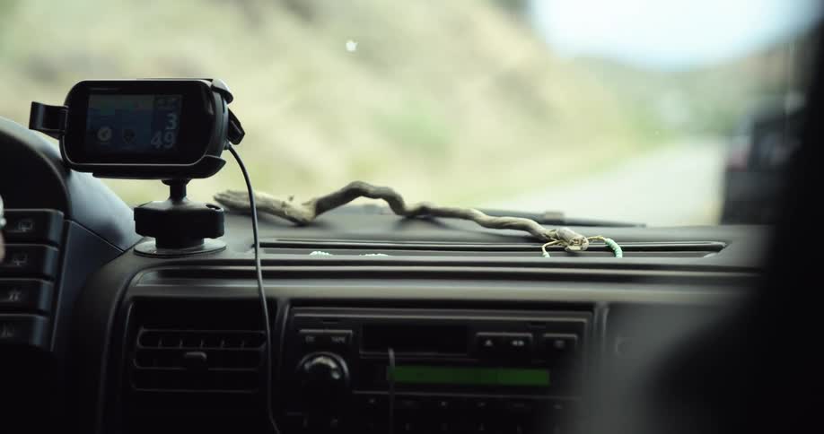 A car driving down a road near a hill