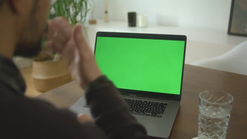 A man is videochatting on a laptop indoors