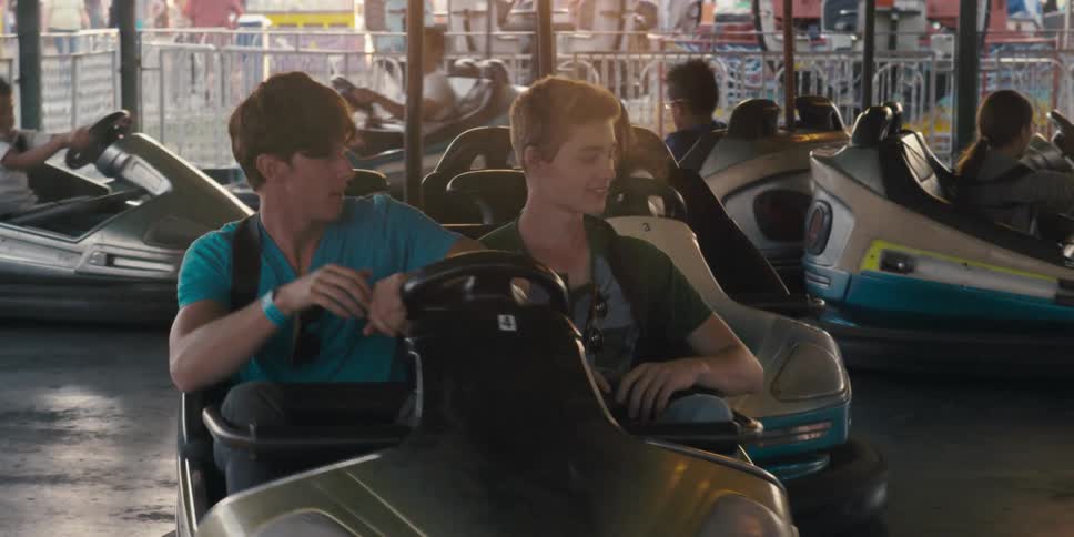 Two male friends driving a bumper car in an amusemet park