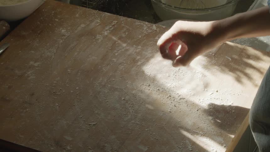 A person wipes flour on the cutting board