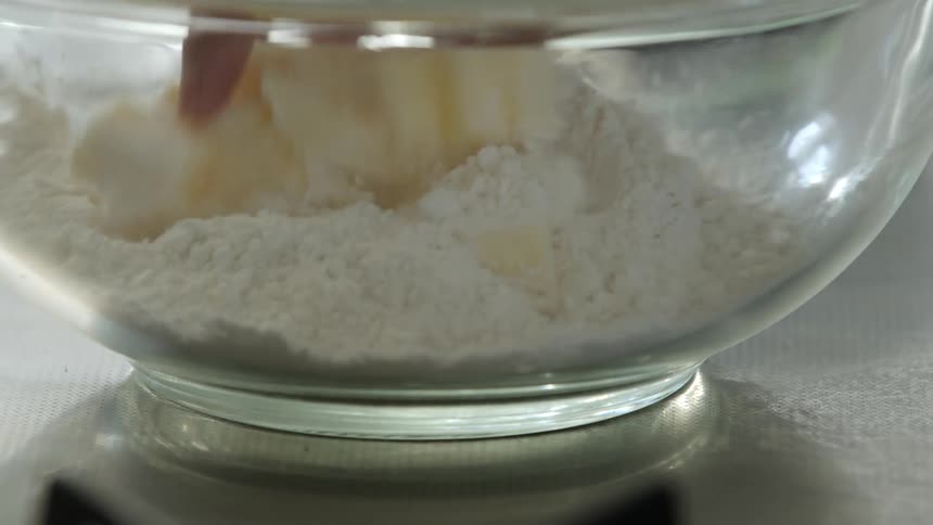 A person mixing butter and flour in a bowl with their hand