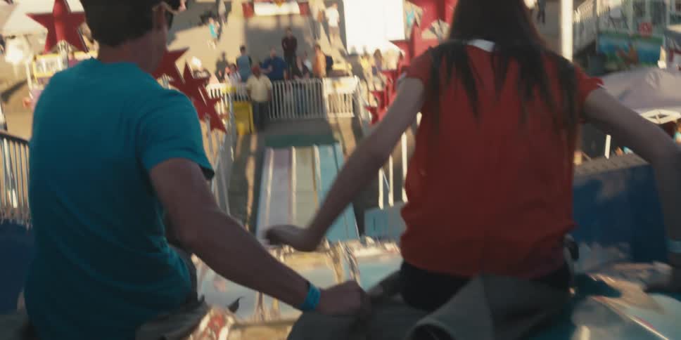 Two people riding down a slide at an amusement park