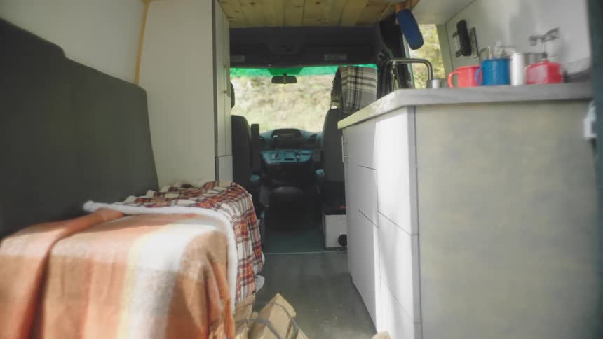 A vehicle with chairs blankets and a sink with cups