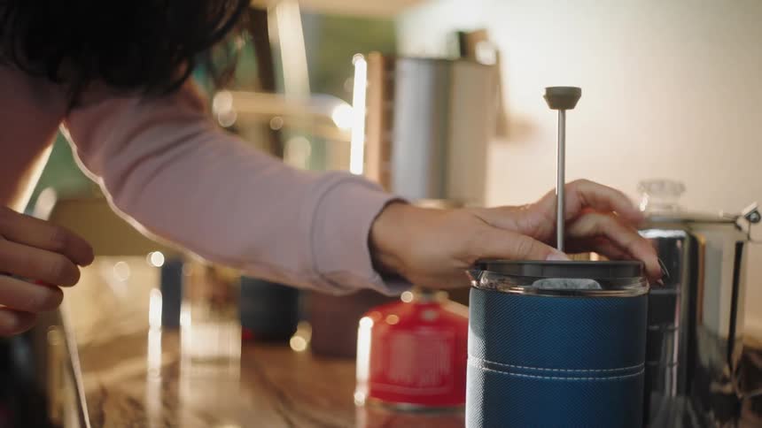 Woman brewing coffee on the kitchen counter top at home