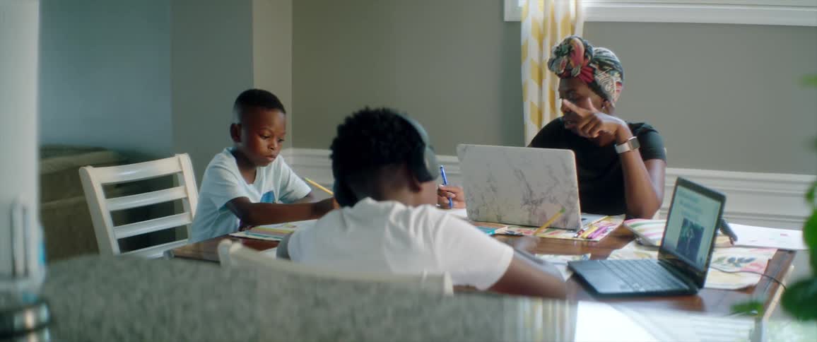A family is sitting at a table and doing school work
