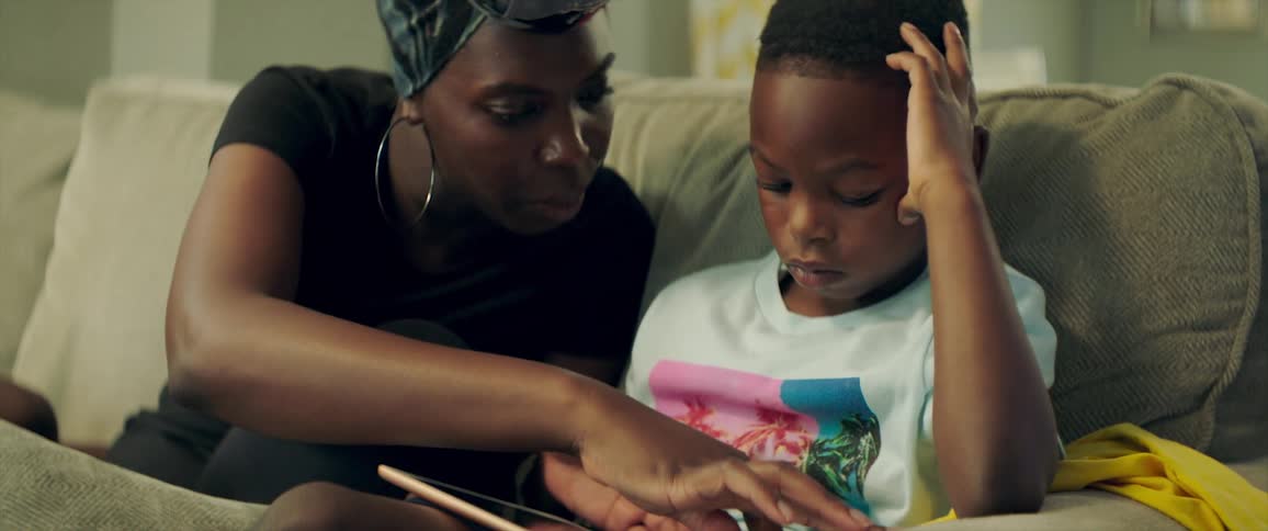 A woman is looking at a tablet with her son