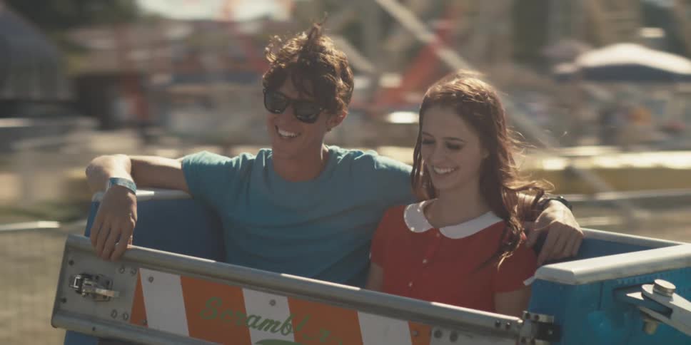 A man has his arm around his girlfriend as they spin around in a carnival ride